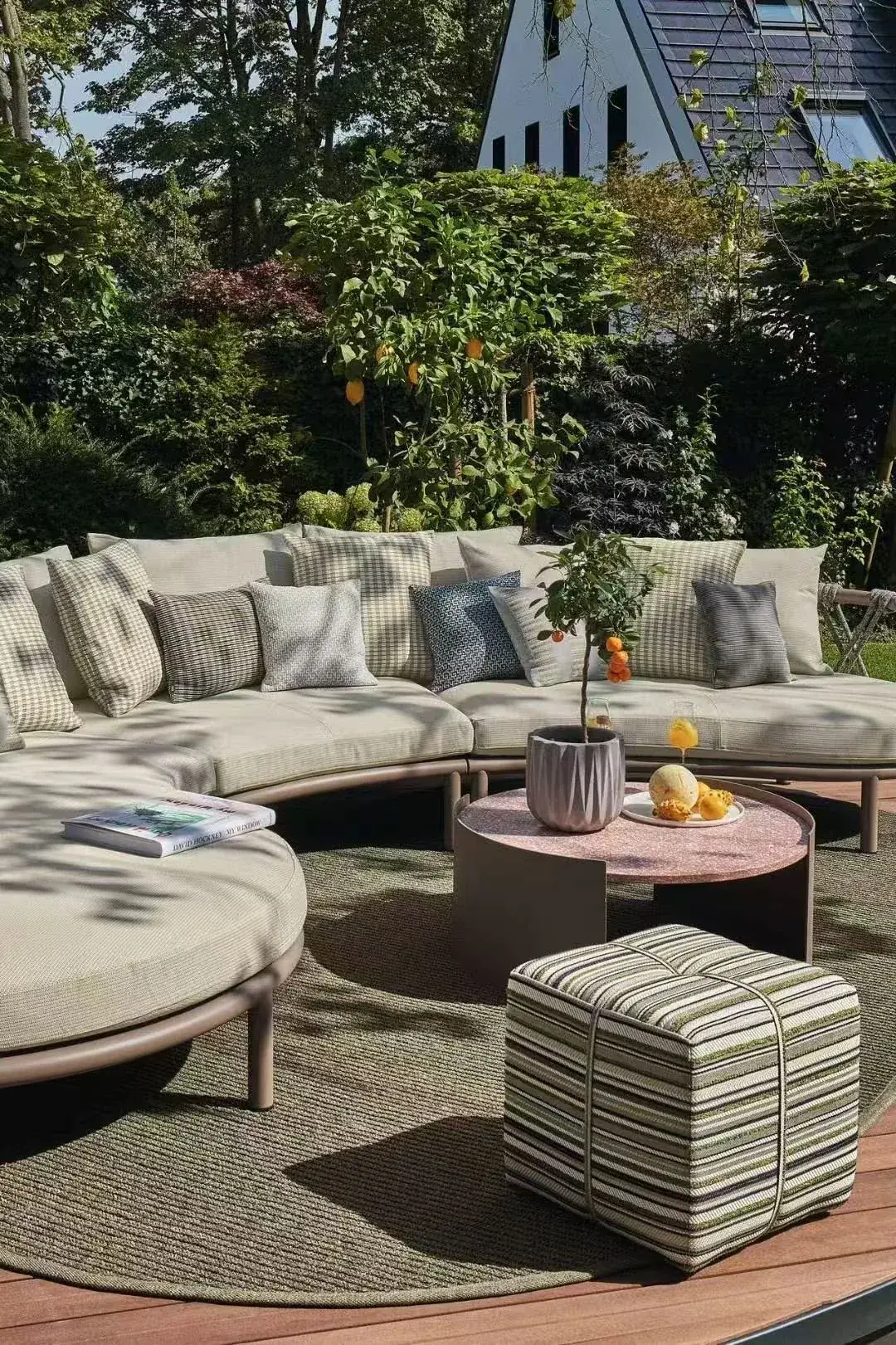 Outdoor sofa with patterned and plain cushions in a garden setting