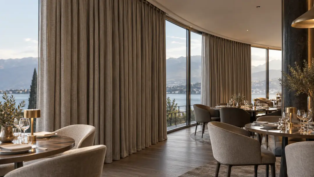 Heavy pleated curtains on a curved track along a curved glass wall in a hotel restaurant