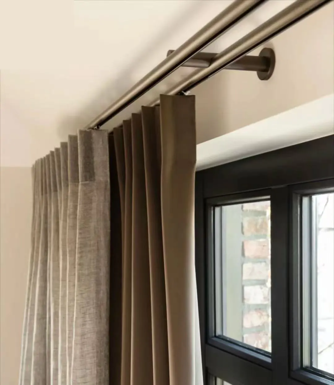 Pleated curtain on a double metal track beside a window